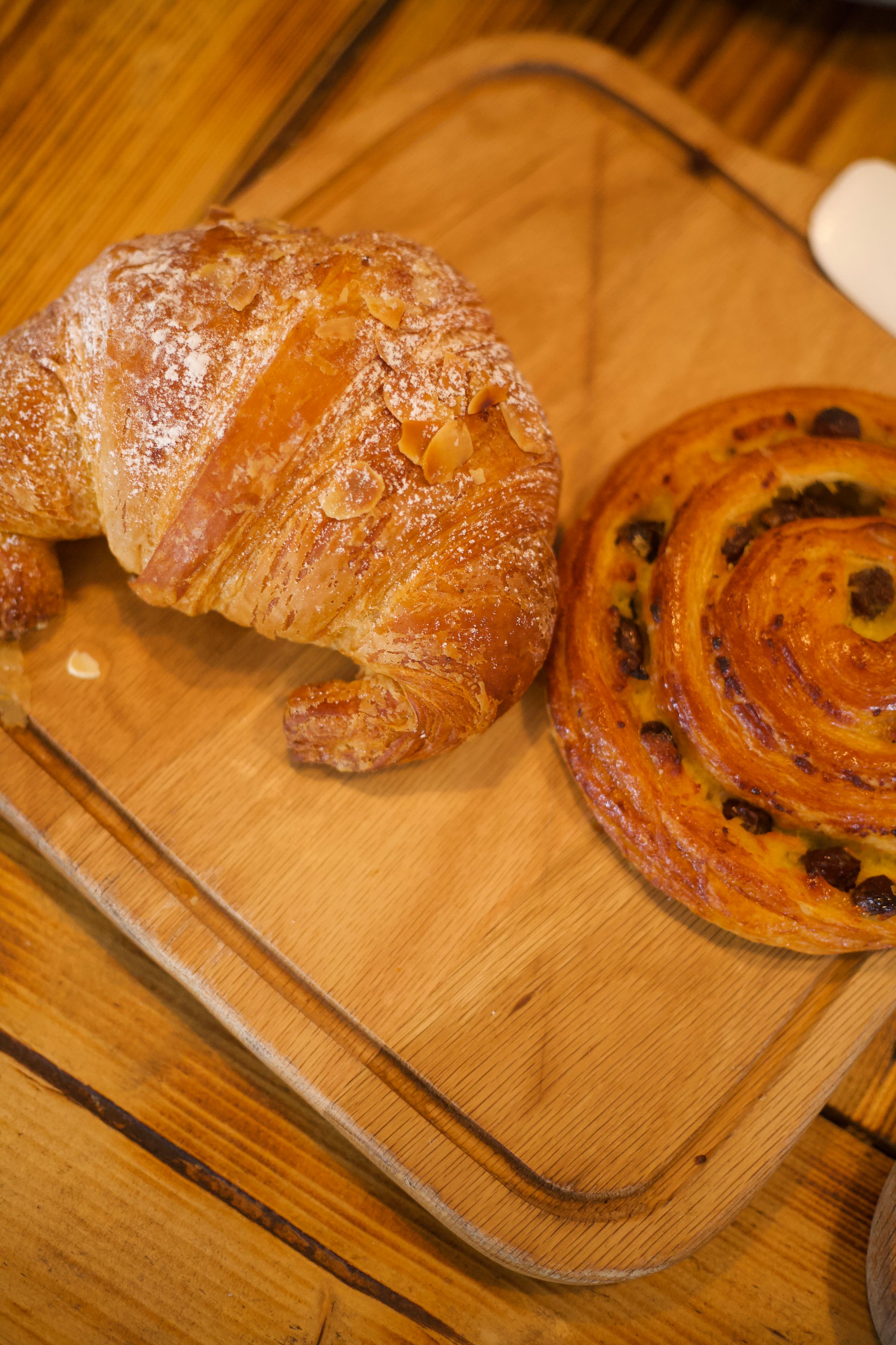 Fresh Danish pastries including almond croissant and raisin swirl on a wooden board